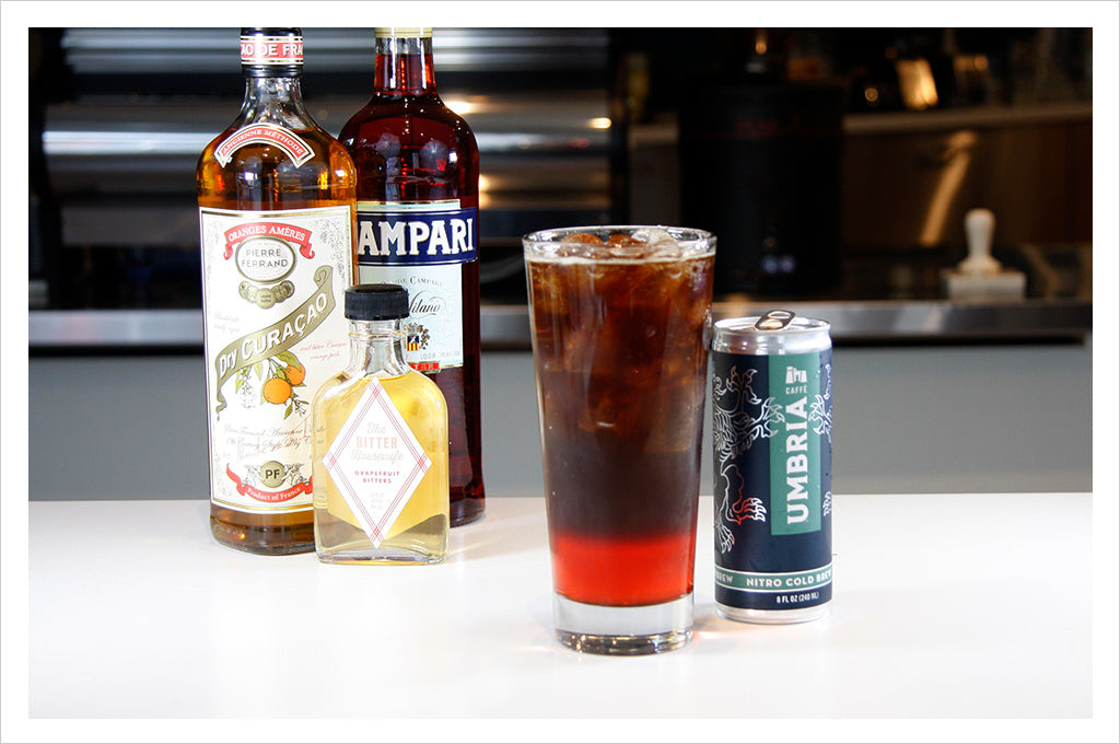 a glass with a coffee cocktail, a can of nitro cold brew, and various spirits bottles