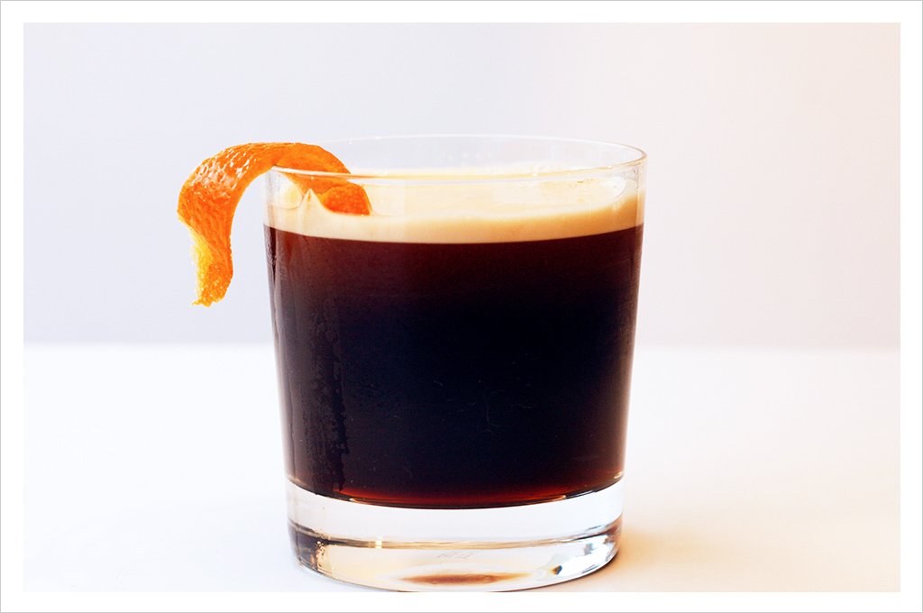 a photo of a coffee cocktail in a glass with an orange twist