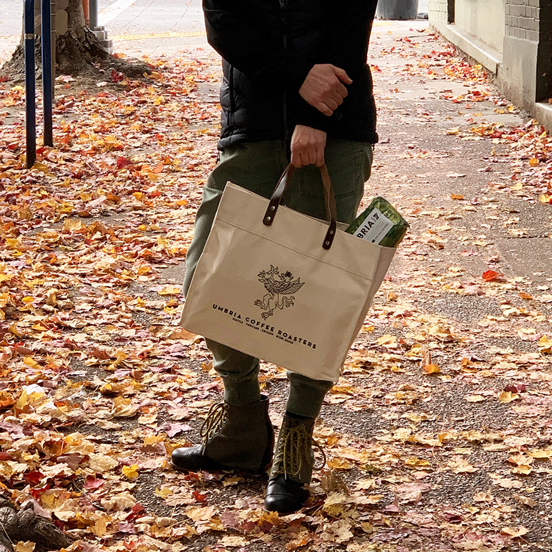 a person holding a beige logo tote on the street